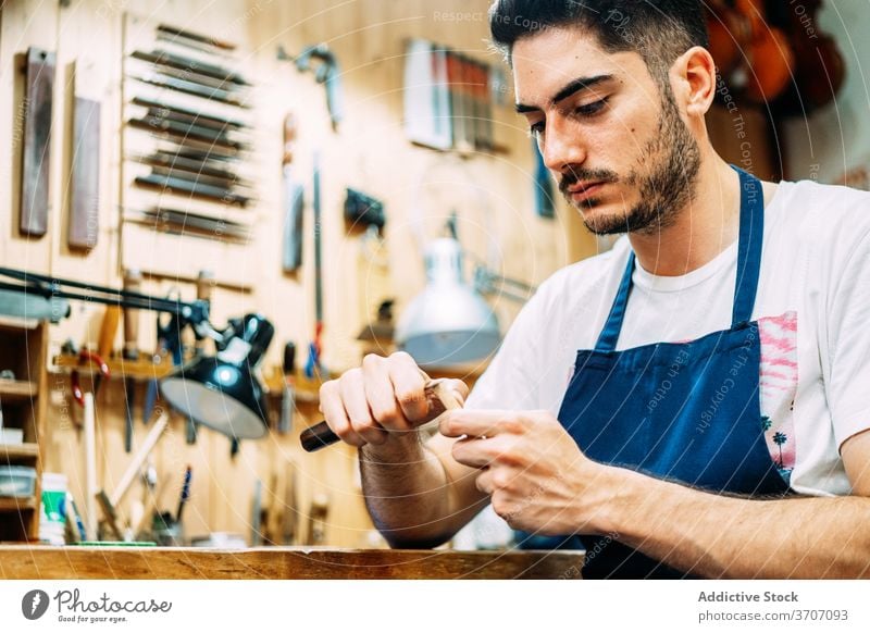 Instrument maker working with hair for bow luthier craftsman tool repair artisan restore workshop instrument equipment skill master male concentrate focus busy