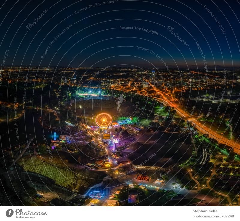 an impressive night view photo over Munich from the Olympic Tower at the ImPark festival at night with an illuminated ferris wheel. munich fun muenchen