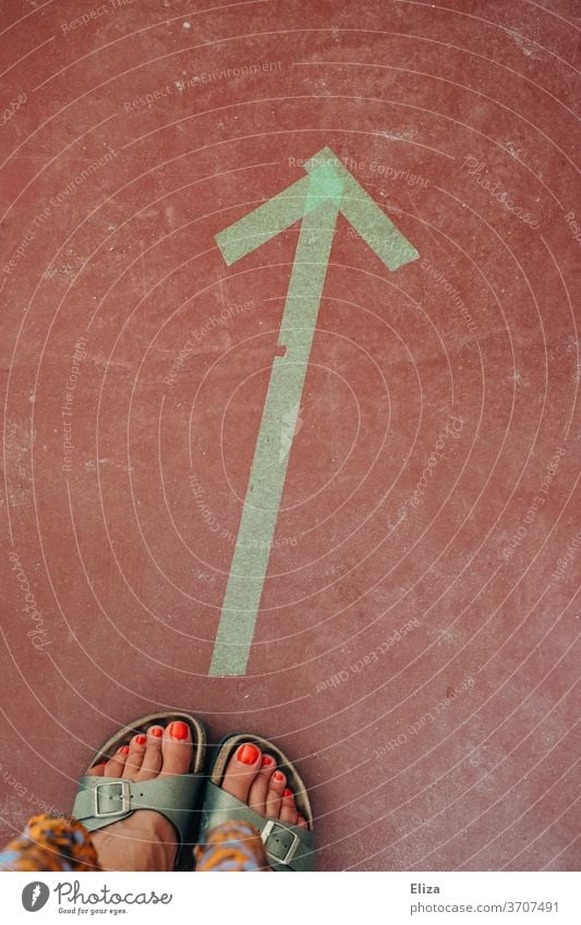 Women's feet in sandals in front of a directional green arrow on the ground Arrow Direction Orientation Green Ground Women's Feet Woman Feminine Emancipation