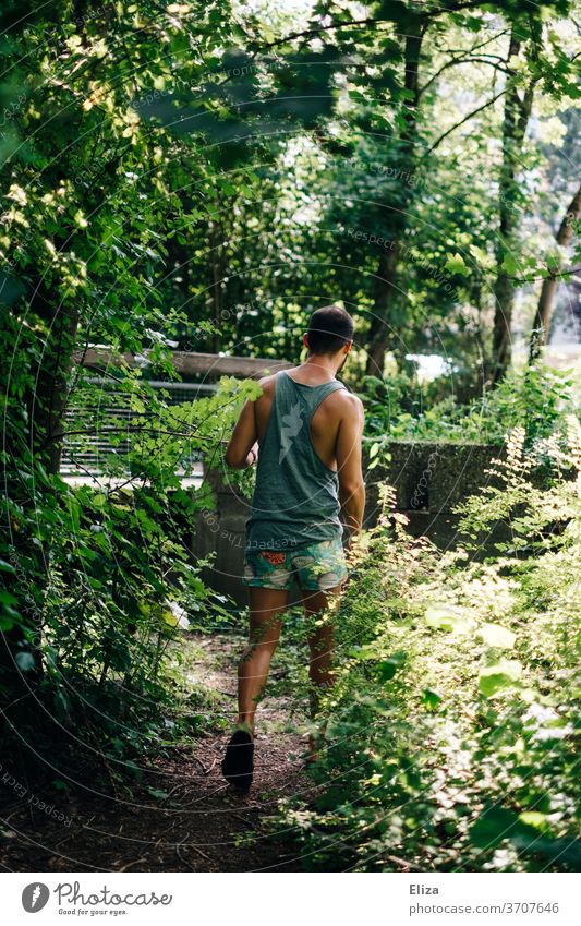 Man from behind in summer clothes taking a shortcut through the bushes Summer shrubby path abbreviation Nature Going st Summer clothes Summery short pants