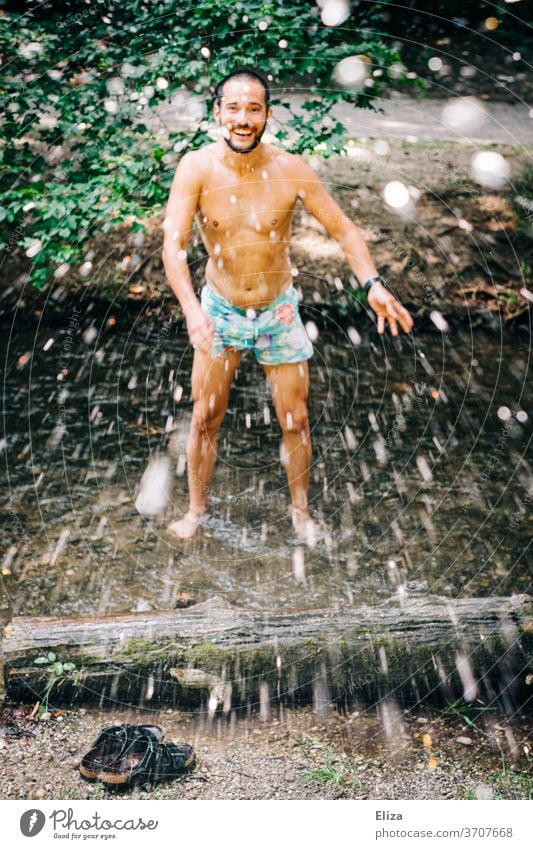 A man bathes in a stream in summer and splashes with water. Refreshing cooling off in this heat. Man Inject Water splashing Refreshment Joy Summer Wet