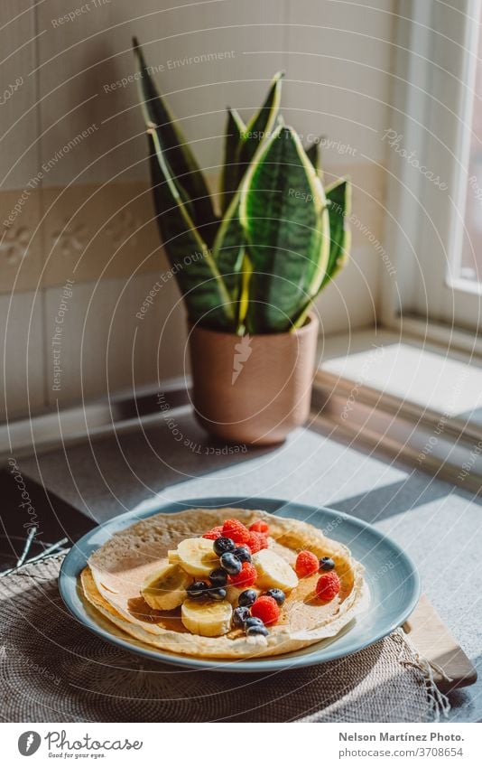 Delicious crepe with bananas, blueberries, raspberries and honey. It is lit with a nice natural light in the kitchen. food dessert delicious sweet healthy