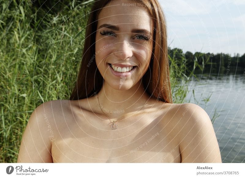 Close portrait of a young woman in a lake in front of reeds Light Athletic Feminine Emotions emotionally Looking into the camera Central perspective