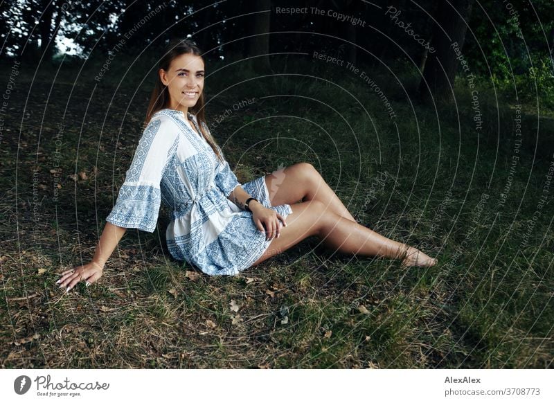 Portrait of a young woman in white-blue patterned summer dress in nature Light Athletic Feminine Emotions emotionally Looking into the camera portrait