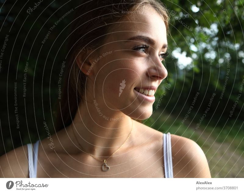 Lateral, close portrait of a young woman in nature Light Athletic Feminine Emotions emotionally Looking into the camera Central perspective