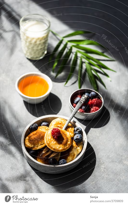 Mini pancakes with fresh berries and honey on a grey table. Shadows and light, rich in contrast. mini Breakfast Berries Honey Dessert Sweet Pancake Fresh