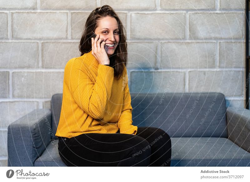Cheerful young woman talking on smartphone happy casual cheerful mobile communicate satisfied female news modern loft laugh device gadget connection