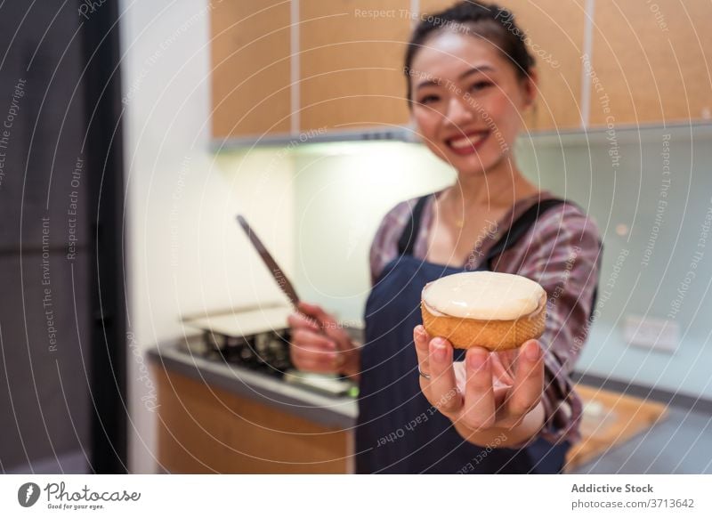 Satisfied baker showing delicious tart woman satisfied pastry cream home small business spatula filling cheerful demonstrate smile dessert food prepare kitchen