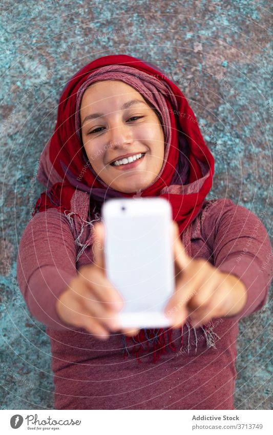 Happy woman taking selfie with mobile phone on street city using smartphone hijab happy female smile cheerful arab ethnic building browsing cellphone online