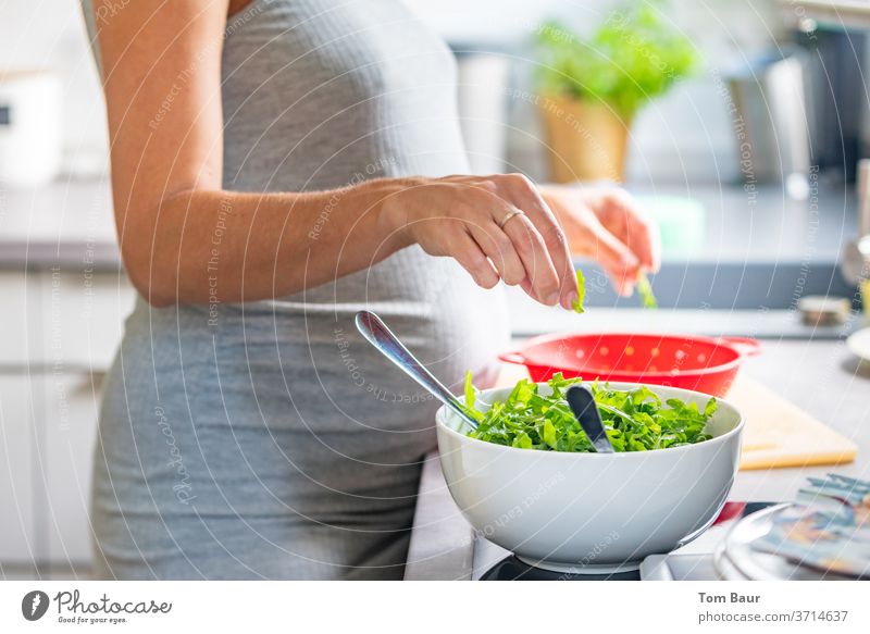Pregnant young woman spreads a delicious salad in the kitchen Lettuce Laundry vegan Vegetarian diet polish Eating Healthy Eating Vegan diet by hand Nutrition