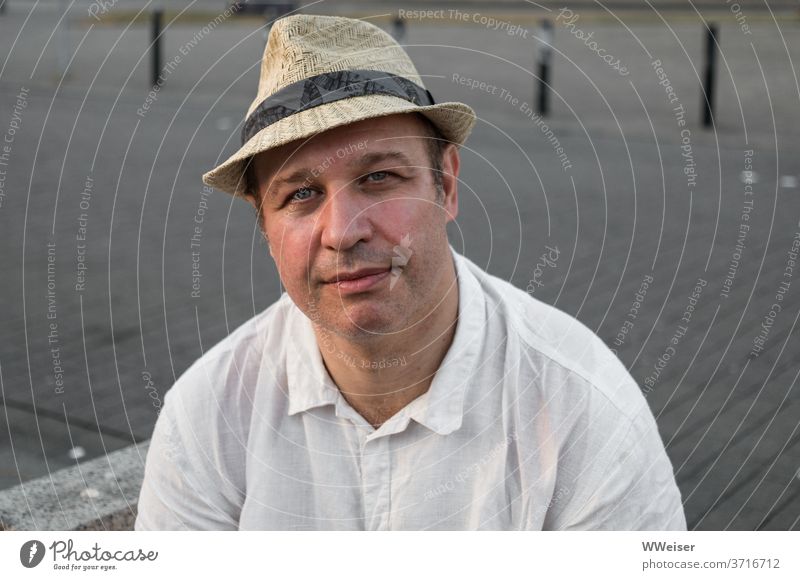 A man in a hat looks friendly and a little bit melancholic into the camera Man person Hat Shirt Summer Face Head portrait kind tired Meditative melancholically