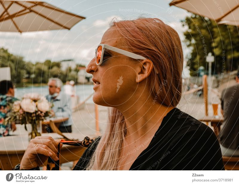 Young woman in a restaurant on the Danube Regensburg Restaurant Sit To enjoy Summer Warmth out Blonde long hairs sunglasses pretty already Meditative Brown