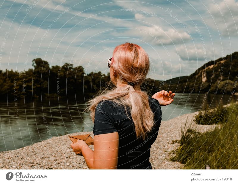 Young woman at the river bank River bank Danube Water Landscape green bushes Nature Blue Sky Sports long hairs Athletic back view sunglasses Clouds girl