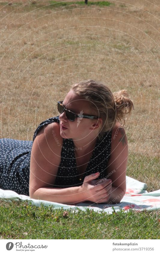 Woman with sunglasses lies on a dry meadow and looks to the left Sunglasses Cool (slang) Park Adults chill seriously Earnest questing Meditative Summer