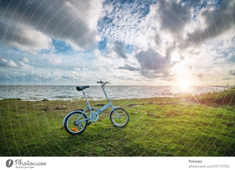 Foldable bike by the ocean at sunset sunny compact sunrise bright pendling scenery summer pedal cycling bicycling outdoors lifestyle blue landscape sea