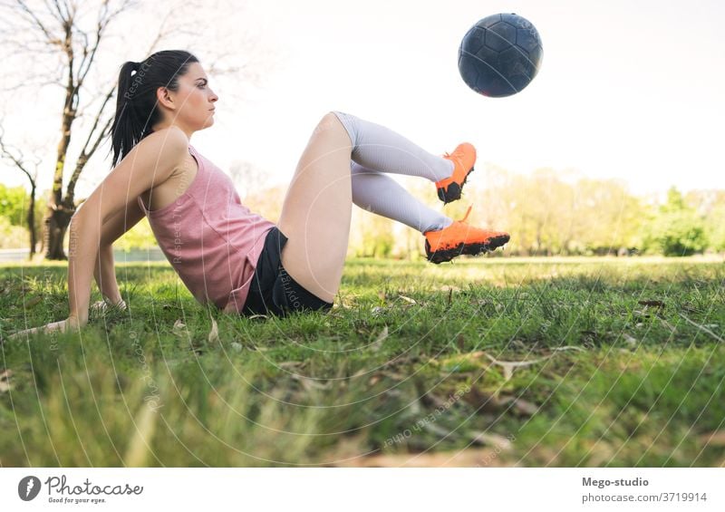 Young female soccer player practicing on field. young woman football focused exercising athleticism trick summer sports activity recreational players