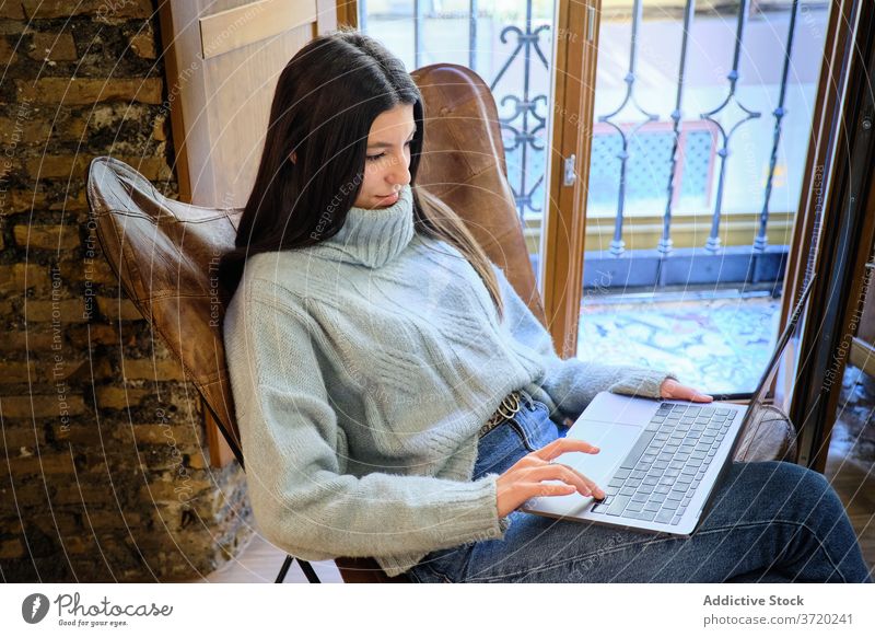 Woman working on laptop at home freelance remote woman typing project surfing using startup female cozy armchair internet gadget busy device browsing business