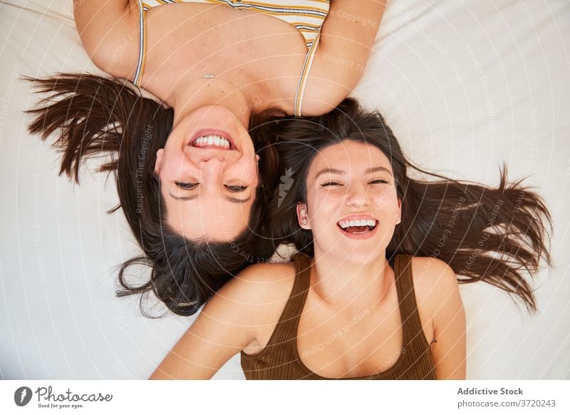 Smiling women resting on bed together friendship best friend lying weekend enjoy cheerful soft friendly home relax happy smile comfort glad relationship harmony