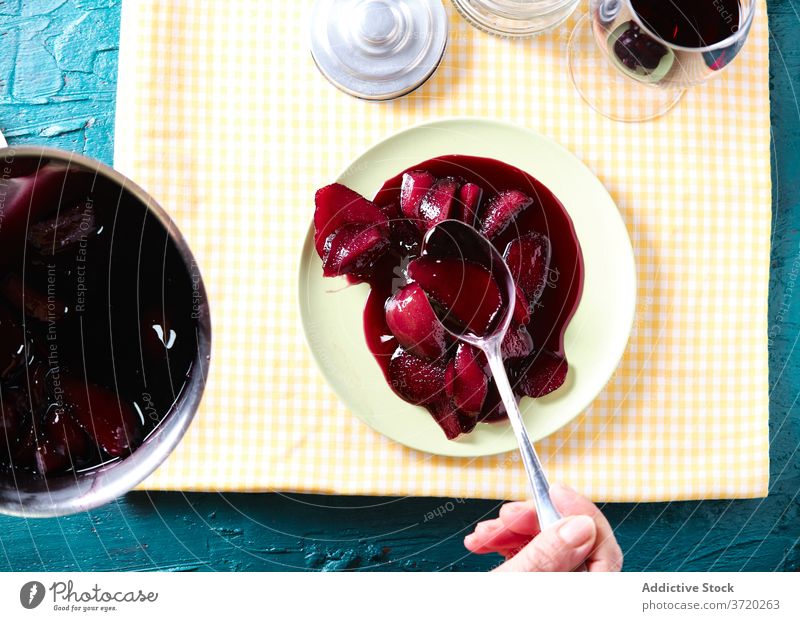 Crop woman at table with poached pears red wine sweet dessert fruit portion delicious female drink food beverage fresh yummy snack dish meal home treat gourmet