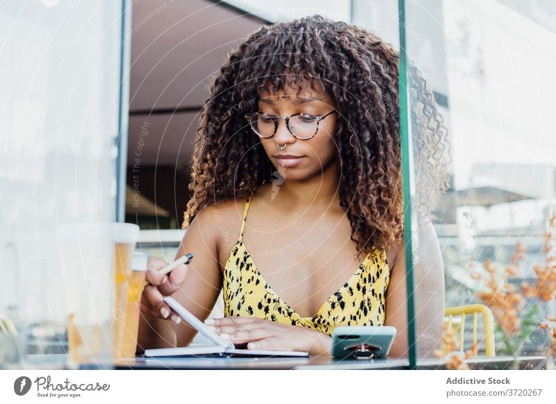 Female freelancer taking notes in notebook woman cafe work take note entrepreneur summer notepad write female ethnic black african american remote table modern