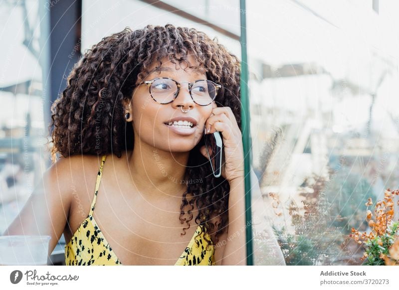 Black woman talking on smartphone using cafe relax entertain conversation speak communicate female ethnic black african american charming enjoy connection chat