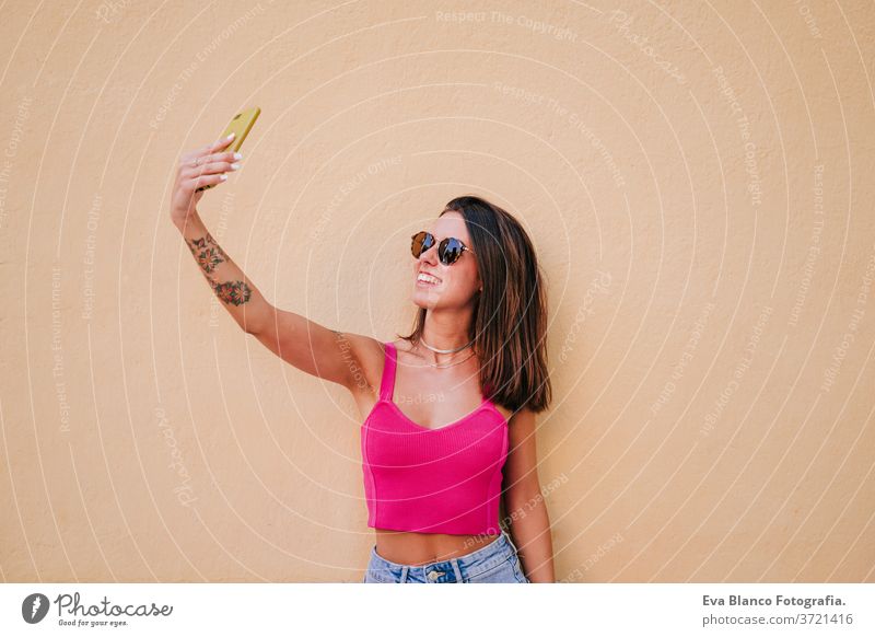 beautiful young woman outdoors taking a picture with mobile phone. Technology and lifestyle street urban smiling city technology tattoo modern happy summer