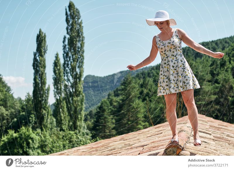 Calm woman standing on rooftop in summer relax mountain tranquil tile highland nature female sunlight summertime dress hat sunhat building enjoy vacation sit