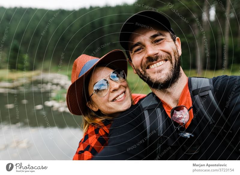 Selfie of a young couple in the mountains by the river 30s active adult adventure backpack backpackers backpacking boyfriend camera casual caucasian cheerful