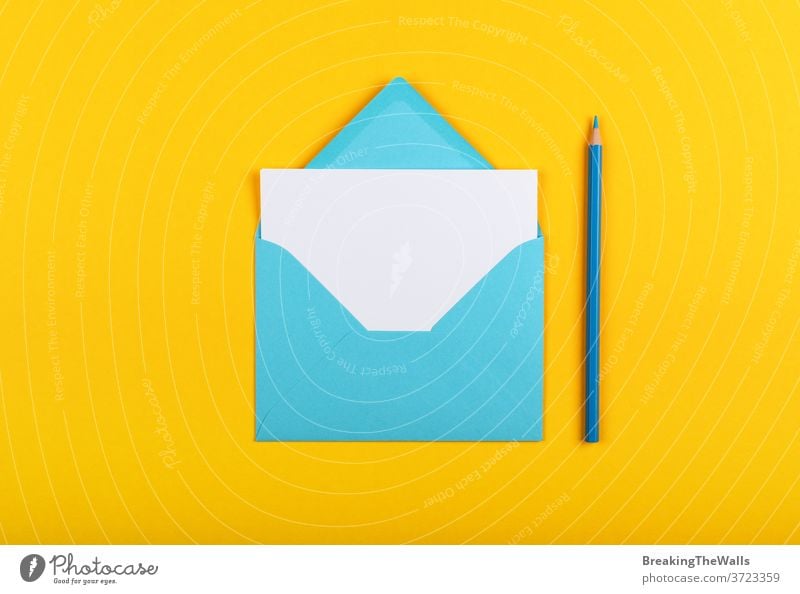 Open blue paper envelope over yellow Envelope one white sheet pencil wooden pastel vivid background closeup color colorful multicolor post mail message