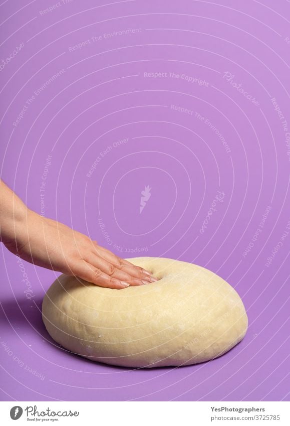 Uncooked dough isolated on purple table. Woman hand pressing the dough background bake bakery baking ball bread bread dough buns concept cooking copy space