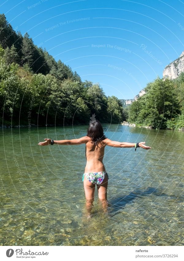 Rear view of a arms raised woman standing into the river while bathing 1 water wet young adult hair beautiful beauty girl summer female person day nature people