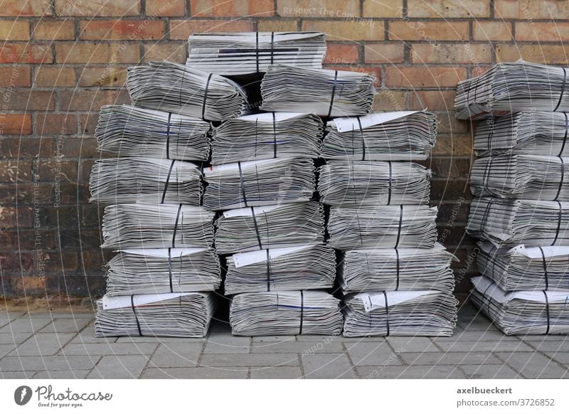 newspaper stack on street pile bundle bunch press media heap delivery piled stacked bundled bunched tabloid nobody sidewalk background footpath pavement