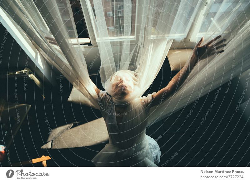 Overhead portrait of a blonde woman. She is with open arms, wrapped in tulle curtains. courtains natural light caucasian Portrait photograph pretty Beautiful