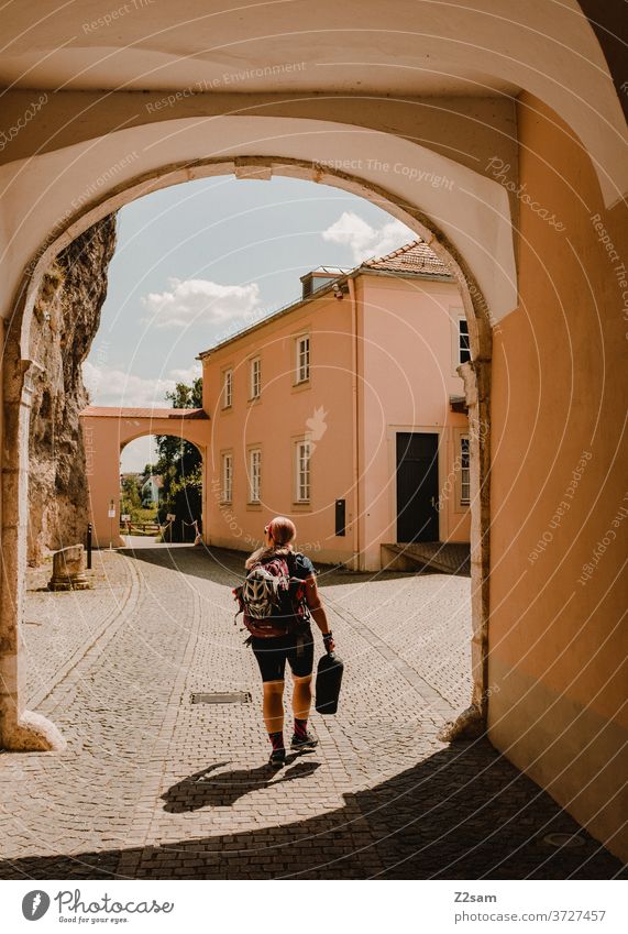 Young cyclist in the archway Cyclist Bicycle travel Backpack Bag Sports Athletic Summer Sun Sky weltenburg monastery Blonde girl Woman youthful teen already