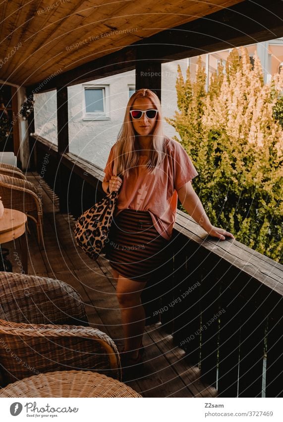 Young woman on the balcony of a holiday flat holidays vacation dwell Balcony sunglasses Girl Blonde pretty Bag Summer Sun Warmth Garden at home