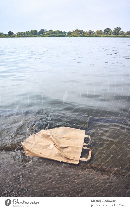 Discarded shopping paper bag in water. garbage recycling pollution recyclable environment trash nature litter environmental sea river recycle discarded problem