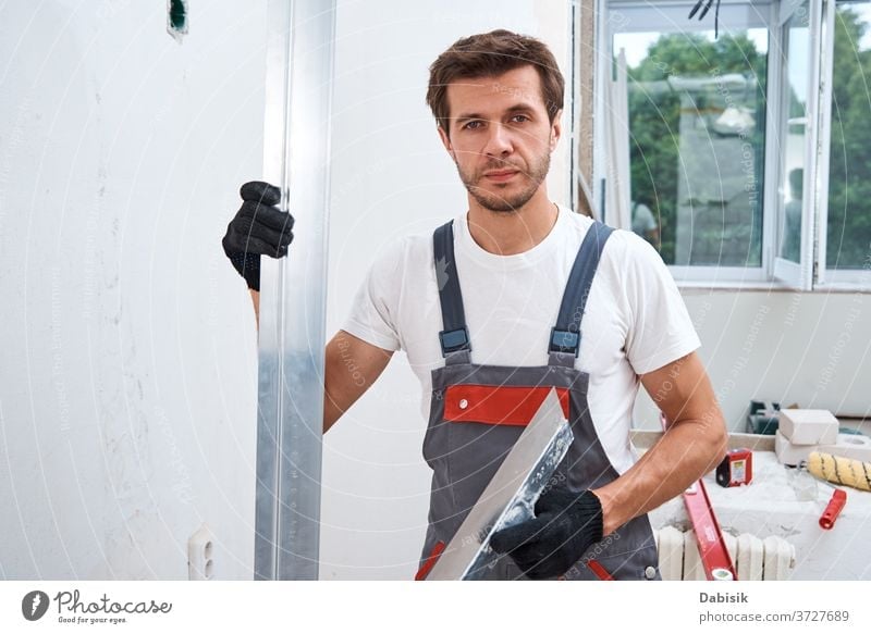 Renovation concept. Male worker plastering a wall using a long spatula renovation man tool stucco industry manual repair construction improvement home building