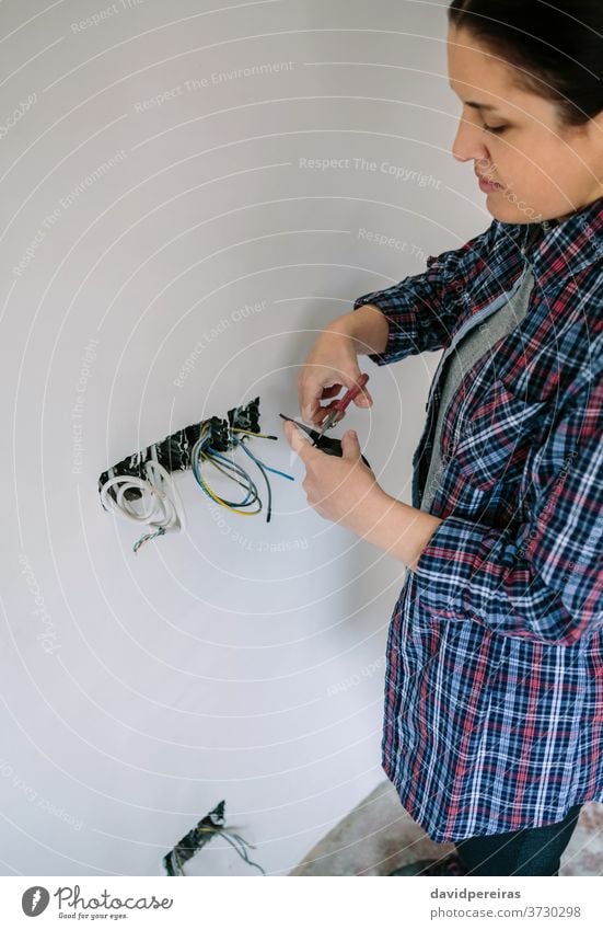Electrician working on the electrical installation of a house electrician female electrical technician cutting insulating tape switches electrical tape