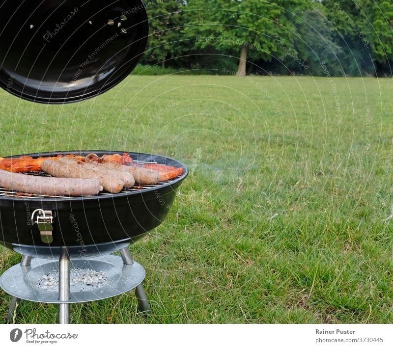 Barbecue season: BBQ grill with steaks and sausages in the park background barbecue barbeque bbq beef charcoal cook cooking delicious fire food grass grilled