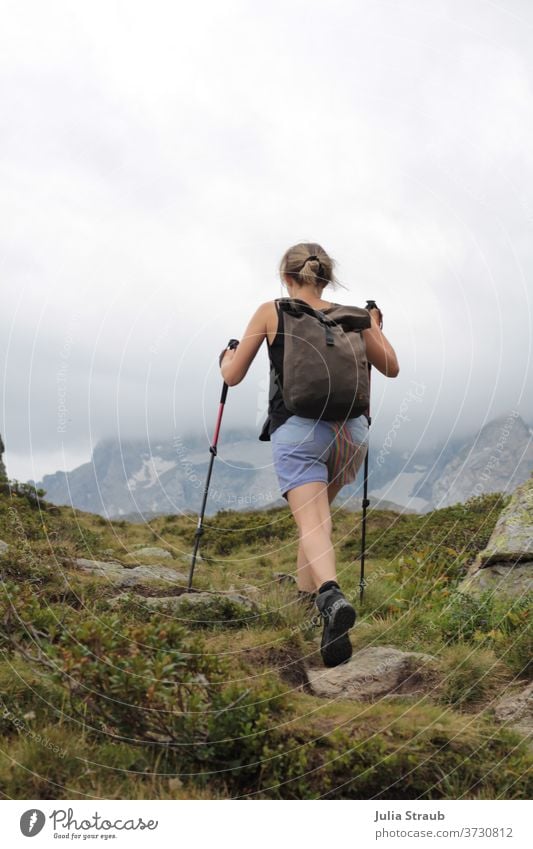 Woman walking in the mountains with sticks in her hands Hiking Behind Mountain Peak Hiking poles Backpack Backpacking vacation backpacker backpacking Chignon