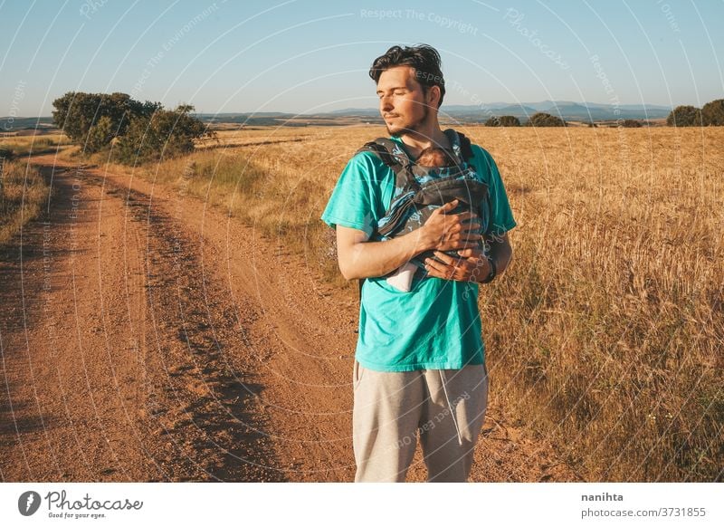 Single male parent carrying her baby with a backpack dad newborn front kangaroo single single parent family outdoors summer fall sunlight take a walk modern