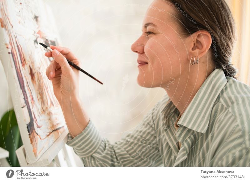 Woman in shirt drawing picture at easel at home artist paint female artistic artwork painter adult occupation education palette canvas person brush paintbrush