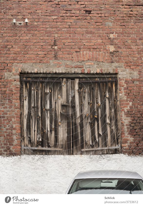 Ancient garage door no longer accepts cars Garage door wood Car roof Wooden gate ancient Weathered inaccessible Brick wall Facade Old Frontal Old and New