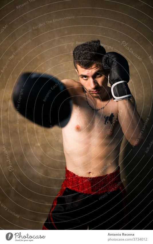 Young man posing in studio shot thai boxer sweat fight kick forearms violence power strong male competitive cardiovascular fighter protection strength athlete