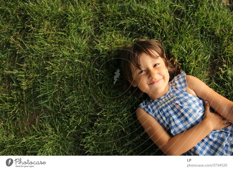 girl smiling at the camera lying on the grass Grass Upper body Portrait photograph Copy Space left Structures and shapes Pattern Abstract Exterior shot