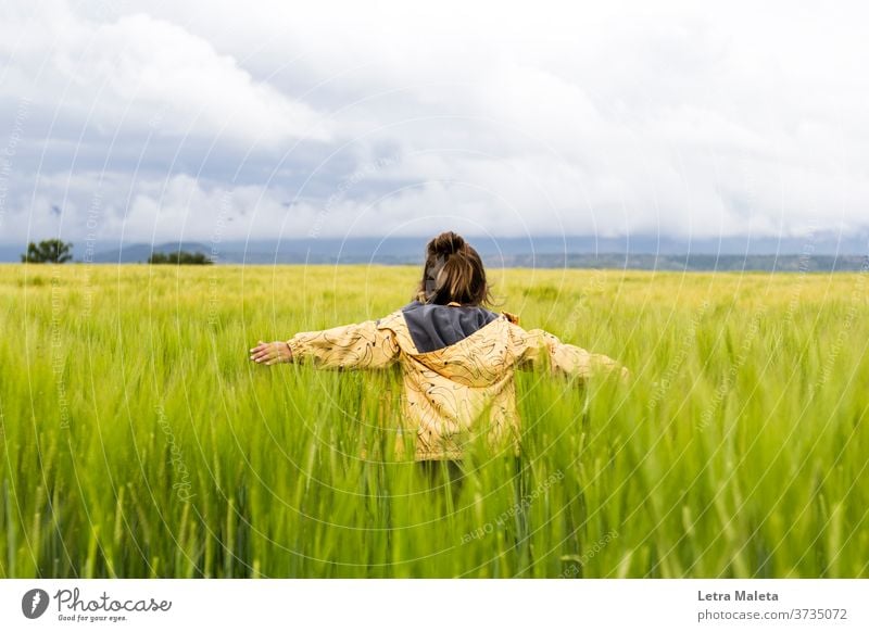 Kid running in the countryside when storm is coming land field spring green lawn plants garden kid yellow pullover freedom free kid nature clouds weather rural