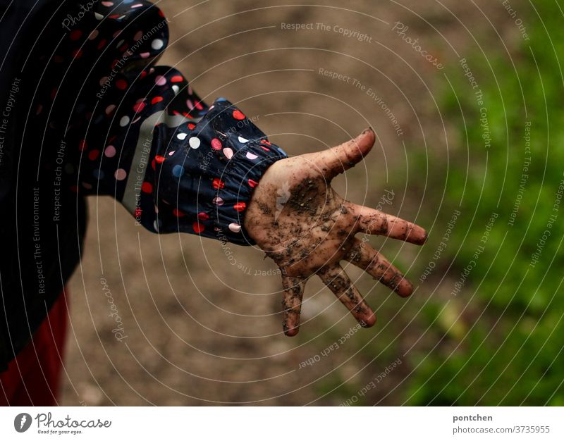 A squishy, dirty child's hand. A child playing in the mud when it rains in rainwear slush filth Children`s hand Dirty Infancy Children's game fun Rain