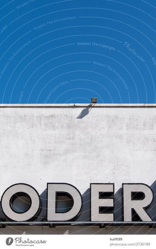 Or, writing on a wall with a blue sky and a spotlight Oder Letters (alphabet) ö D E R Sign Blue sky Concrete wall exterior facade Characters Signs and labeling