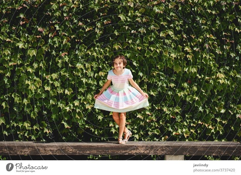 Happy 9-year-old girl in a pretty dress playing kid little child leaves wall urban summer cute city female young style childhood fashion street beautiful