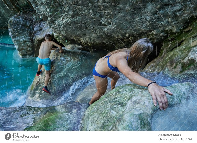 Couple of travelers climbing rock explore couple hike rocky nature vacation mountain effort swimwear adventure tourism cliff lake together journey wanderlust